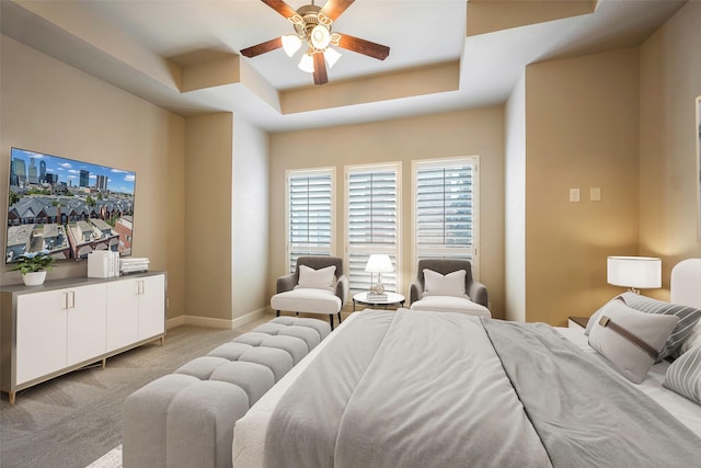 bedroom with ceiling fan, light colored carpet, and a tray ceiling