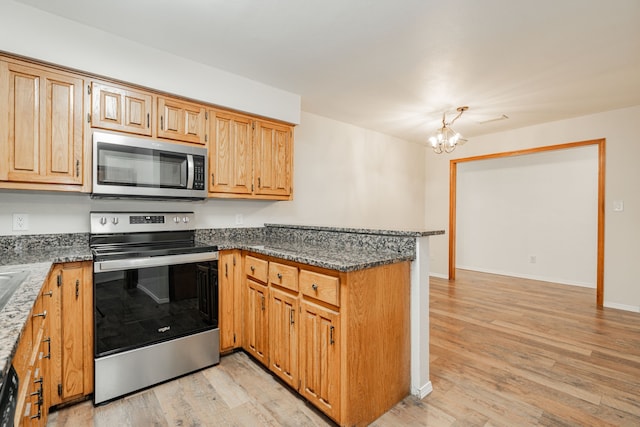 kitchen with light wood-type flooring, dark stone counters, kitchen peninsula, stainless steel appliances, and an inviting chandelier