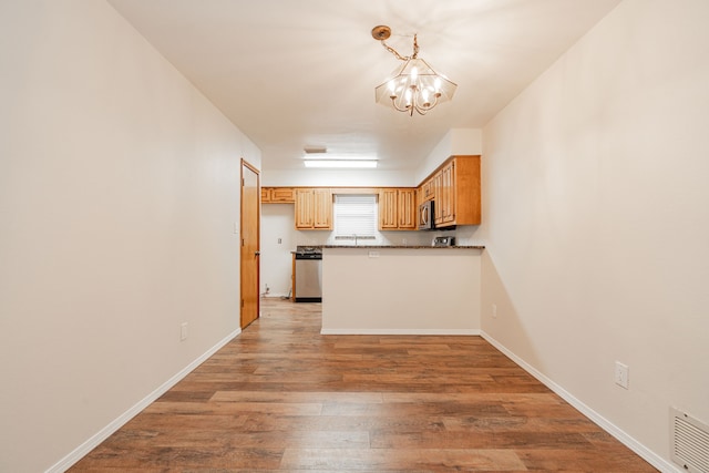 kitchen with decorative light fixtures, stainless steel appliances, light hardwood / wood-style floors, and a chandelier