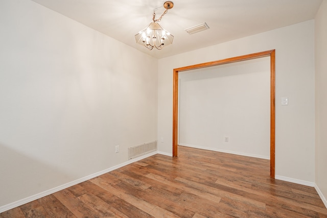 unfurnished room with an inviting chandelier and hardwood / wood-style floors