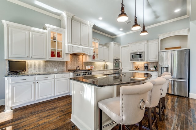 kitchen featuring a kitchen island with sink, hanging light fixtures, stainless steel appliances, and white cabinets