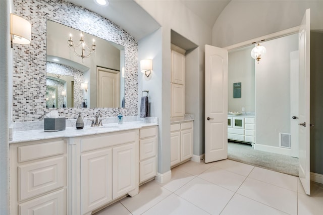 bathroom featuring tasteful backsplash, a notable chandelier, tile patterned flooring, and vanity