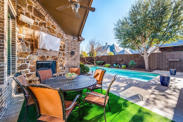 view of swimming pool featuring a patio, ceiling fan, and an outdoor stone fireplace