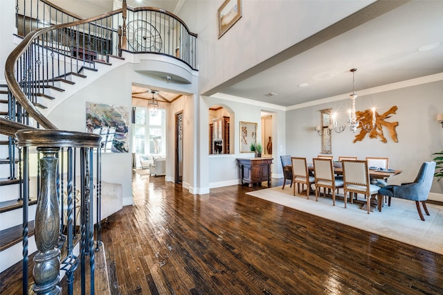 entrance foyer featuring an inviting chandelier, a towering ceiling, dark hardwood / wood-style flooring, and ornamental molding