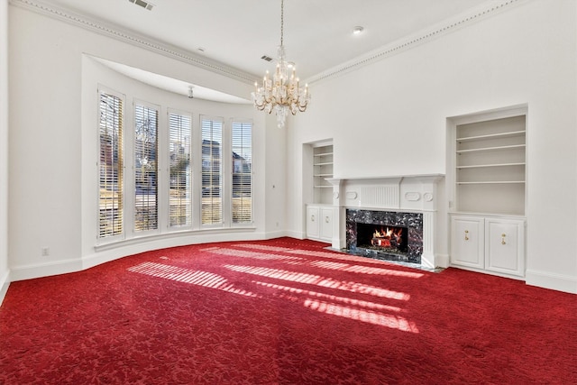 unfurnished living room with a premium fireplace, carpet floors, built in features, and a notable chandelier