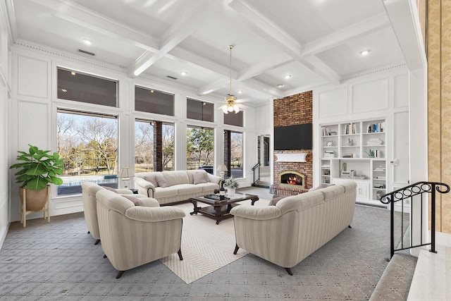 living room with beamed ceiling, a brick fireplace, coffered ceiling, and built in shelves