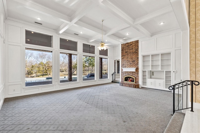 unfurnished living room with built in shelves, a fireplace, coffered ceiling, and beam ceiling