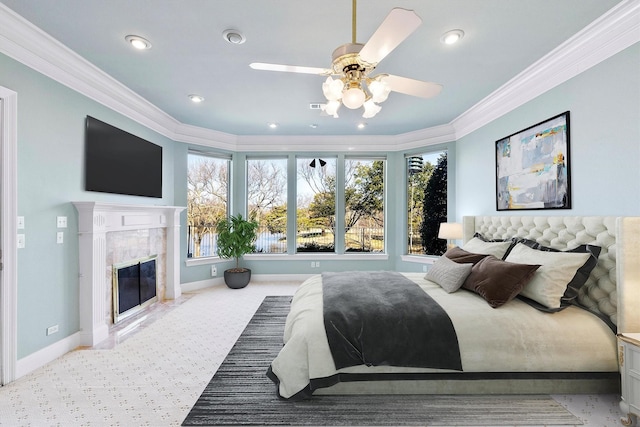 carpeted bedroom featuring crown molding, ceiling fan, and a premium fireplace