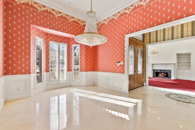 unfurnished dining area with ornamental molding, an inviting chandelier, built in features, and a fireplace