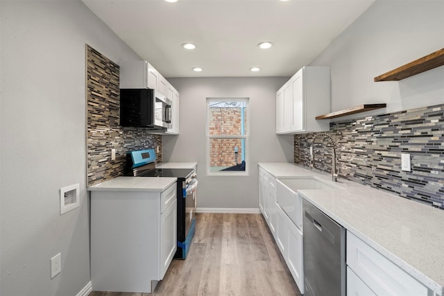 kitchen with sink, white cabinetry, light hardwood / wood-style flooring, stainless steel appliances, and backsplash