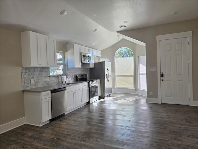 kitchen with lofted ceiling, dark wood-type flooring, white cabinetry, stainless steel appliances, and decorative backsplash