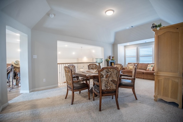 carpeted dining room featuring vaulted ceiling