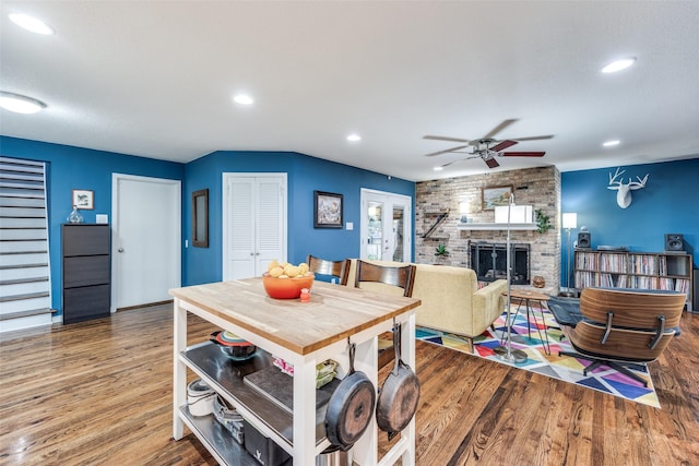 dining space with hardwood / wood-style flooring, a large fireplace, and ceiling fan