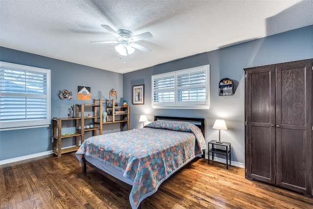 bedroom with ceiling fan, dark hardwood / wood-style floors, multiple windows, and a textured ceiling