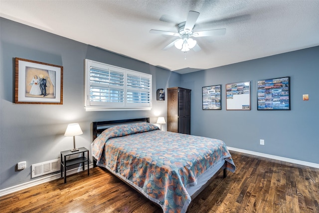 bedroom featuring ceiling fan, dark hardwood / wood-style floors, and a textured ceiling