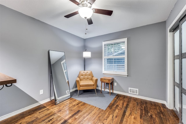 living area with dark wood-type flooring and ceiling fan