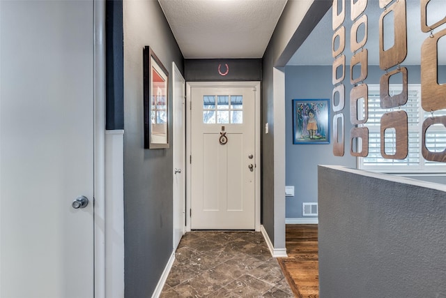 doorway to outside with a textured ceiling