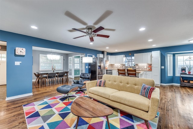 living room with hardwood / wood-style floors and ceiling fan with notable chandelier