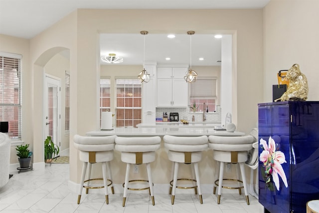 kitchen featuring tasteful backsplash, pendant lighting, white cabinets, and a kitchen breakfast bar