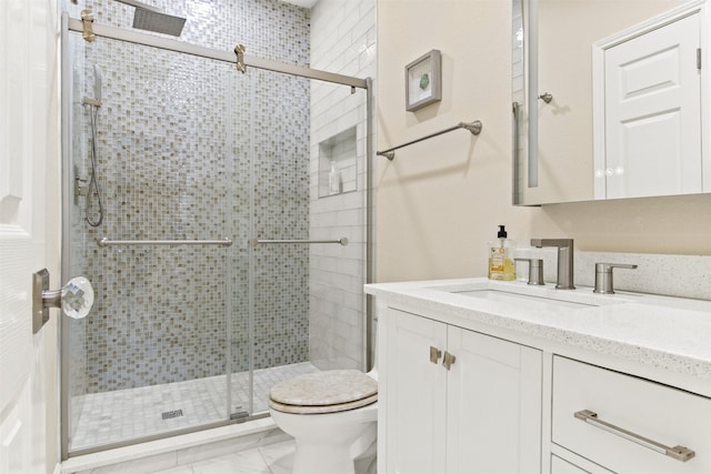 bathroom featuring vanity, toilet, and a shower with shower door