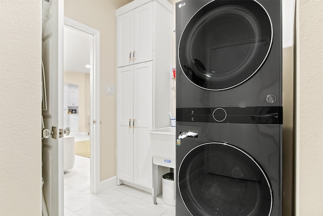 clothes washing area with cabinets and stacked washer and clothes dryer