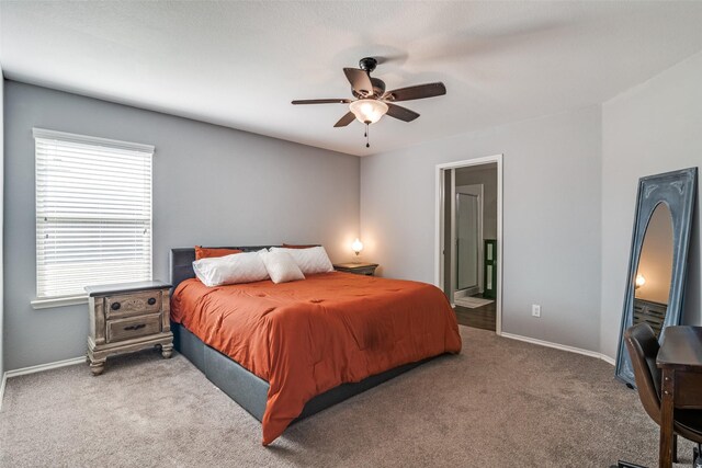 carpeted bedroom with ensuite bath and ceiling fan