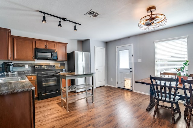 kitchen with a textured ceiling, sink, hardwood / wood-style floors, and black appliances