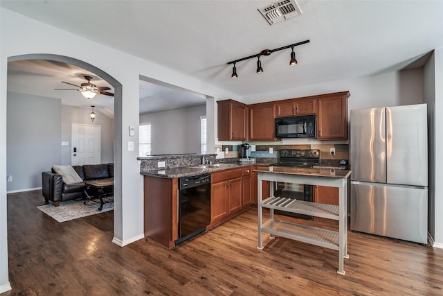 kitchen featuring sink, dark hardwood / wood-style floors, ceiling fan, dark stone counters, and black appliances