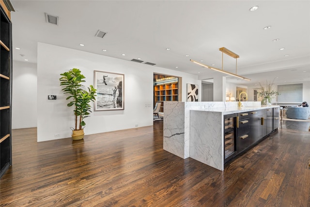 kitchen featuring a large island, visible vents, open floor plan, and dark wood-style flooring