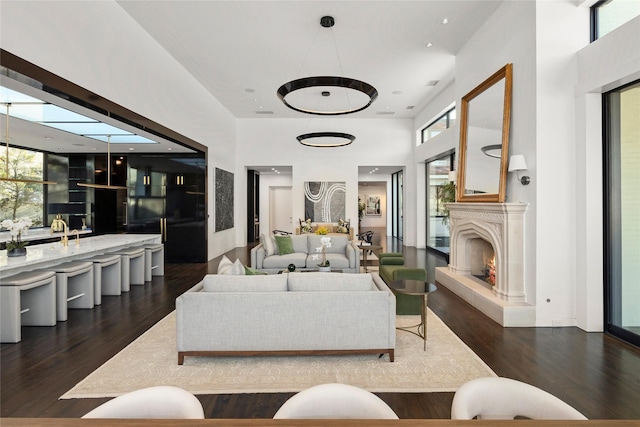 living area featuring a warm lit fireplace, plenty of natural light, and dark wood-type flooring