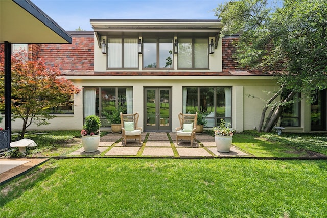 back of property featuring a yard, french doors, a patio, and brick siding