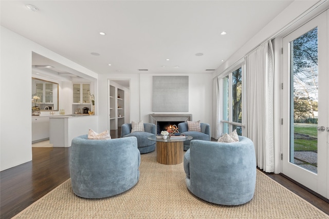 living room featuring a lit fireplace, wood finished floors, and recessed lighting