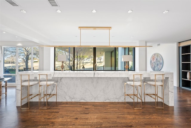 kitchen featuring recessed lighting, visible vents, a kitchen bar, and wood finished floors