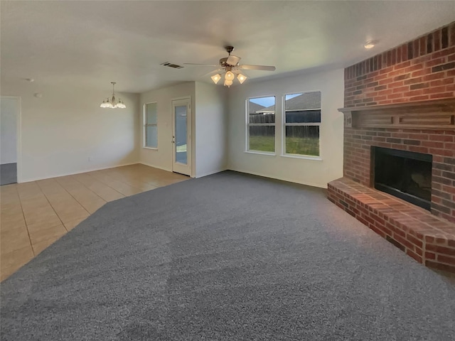 unfurnished living room with tile patterned flooring, a brick fireplace, and ceiling fan with notable chandelier