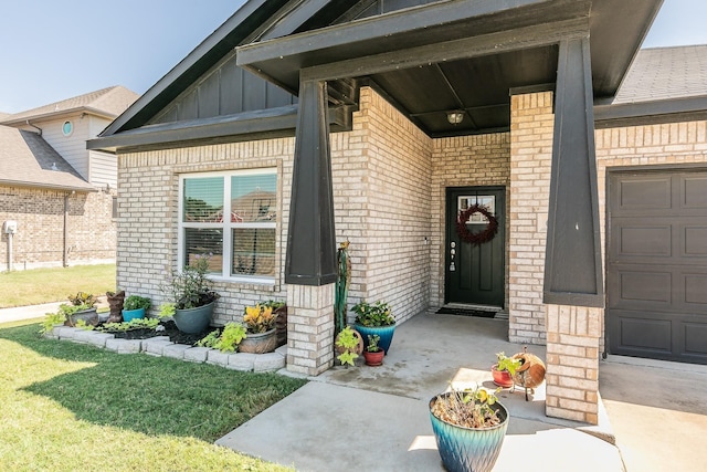 view of exterior entry featuring an attached garage, board and batten siding, and brick siding