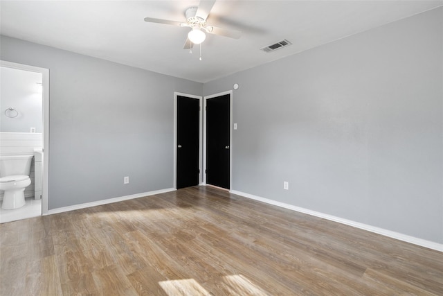 unfurnished bedroom featuring ensuite bathroom, ceiling fan, and light wood-type flooring