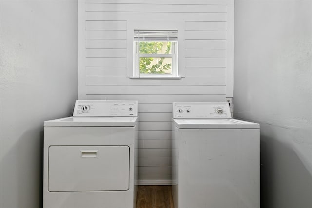 washroom featuring wood-type flooring, washing machine and dryer, and wooden walls