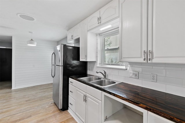 kitchen with wood counters, sink, backsplash, white cabinets, and light wood-type flooring