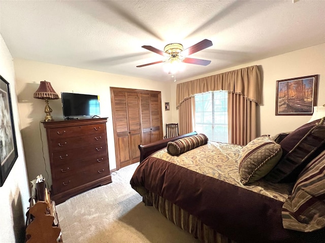 bedroom with ceiling fan, a closet, a textured ceiling, and carpet