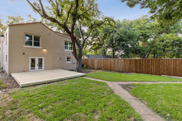 back of property with a yard, a deck, and french doors