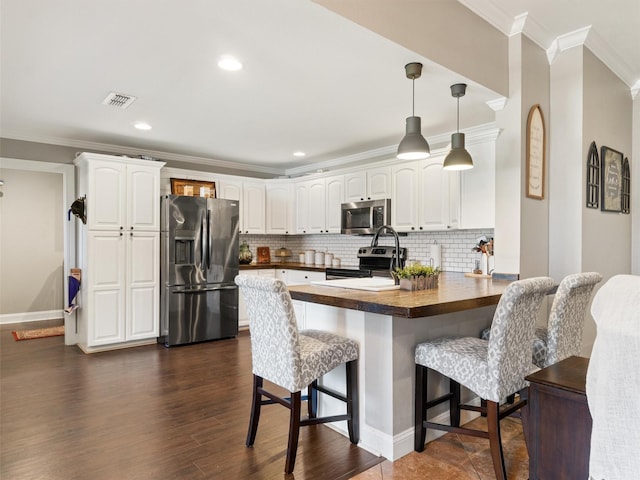 kitchen featuring dark wood-type flooring, a breakfast bar, appliances with stainless steel finishes, white cabinetry, and kitchen peninsula