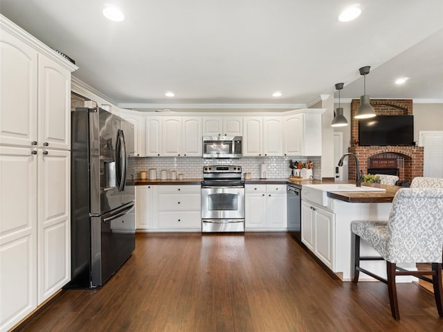 kitchen featuring white cabinetry, stainless steel appliances, dark hardwood / wood-style flooring, and hanging light fixtures