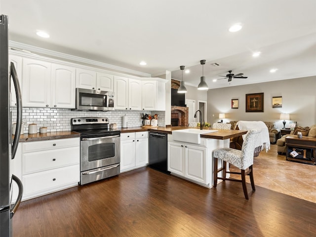 kitchen featuring sink, a breakfast bar, appliances with stainless steel finishes, white cabinetry, and decorative light fixtures