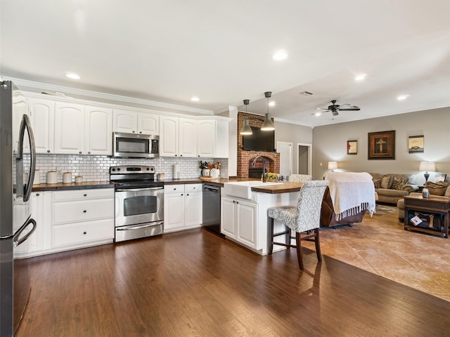 kitchen with hanging light fixtures, white cabinetry, appliances with stainless steel finishes, and sink