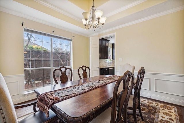 dining room featuring an inviting chandelier, hardwood / wood-style floors, ornamental molding, and a raised ceiling