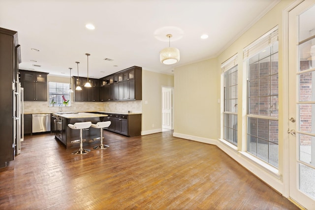 kitchen featuring dark brown cabinetry, a kitchen bar, hanging light fixtures, dishwasher, and a kitchen island