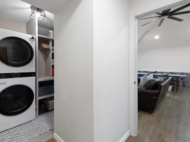 laundry room with stacked washer and dryer, hardwood / wood-style flooring, and ceiling fan