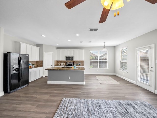 kitchen with tasteful backsplash, appliances with stainless steel finishes, a center island with sink, and white cabinets