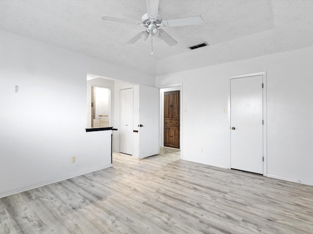 unfurnished bedroom featuring ceiling fan, ensuite bath, a textured ceiling, and light wood-type flooring