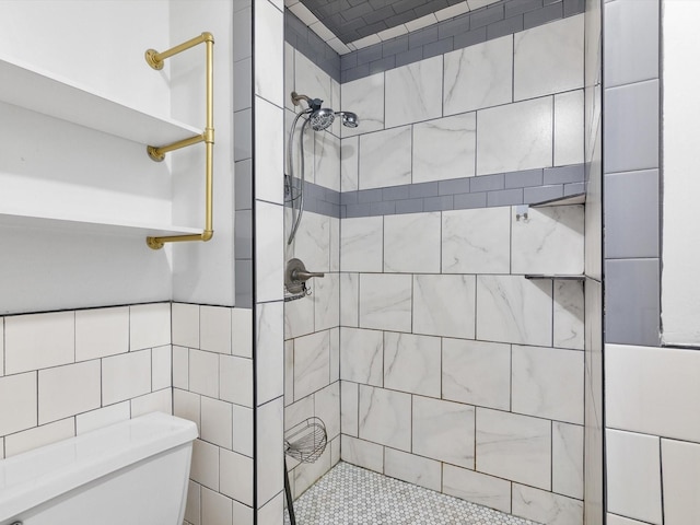 bathroom with a tile shower, tile walls, and toilet